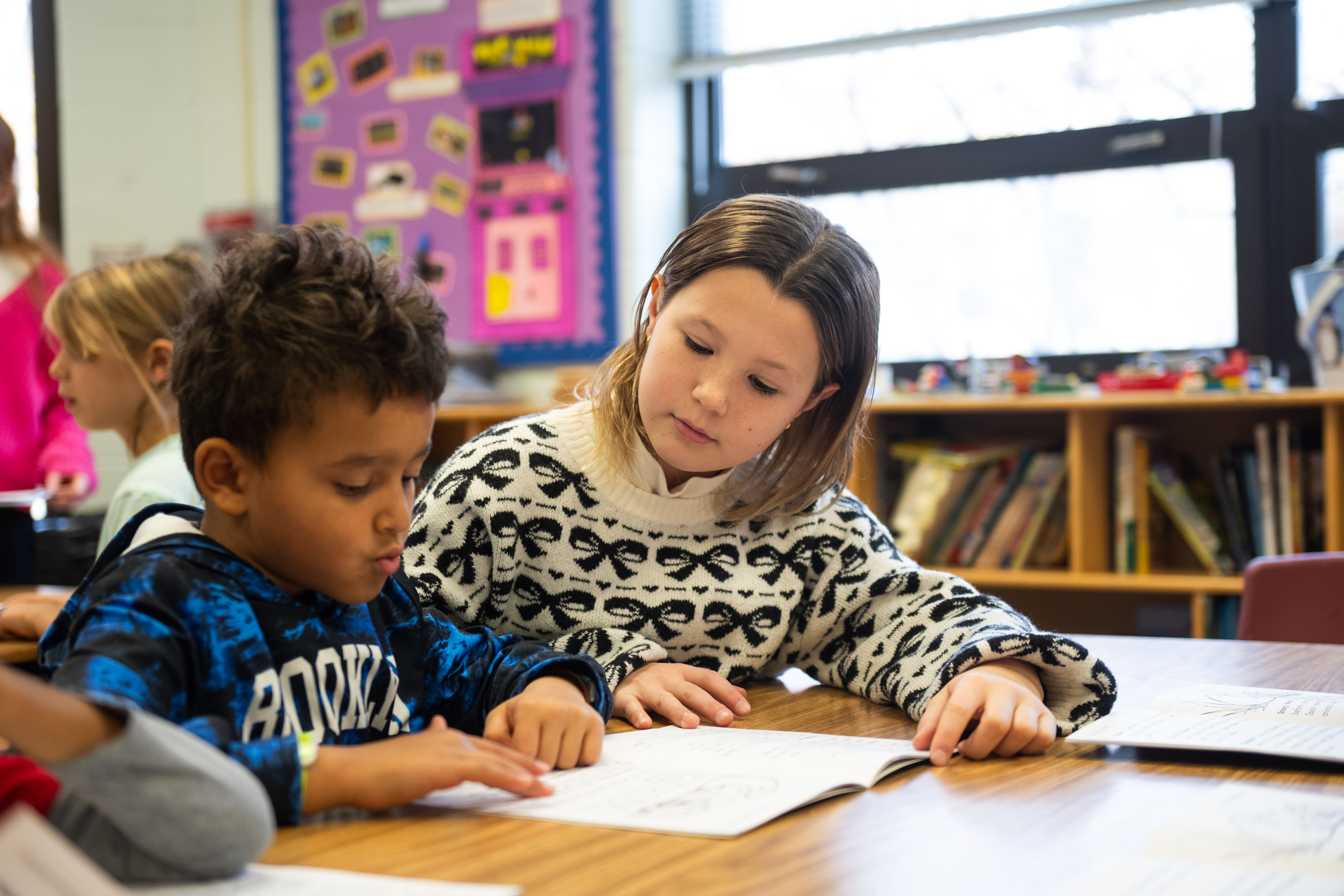 Cardinals Care for Cardinals founder Ruth Gaffiney helps a student with a reading lesson.